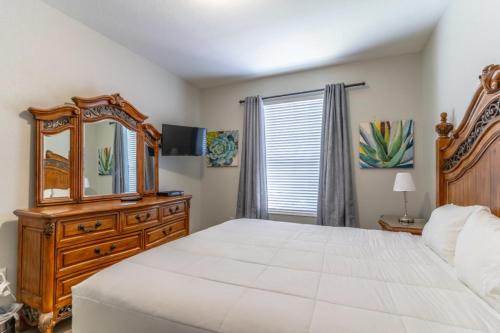 um quarto com uma cama grande, uma cómoda e um espelho. em Apartment at Vista Cay Resort em Orlando
