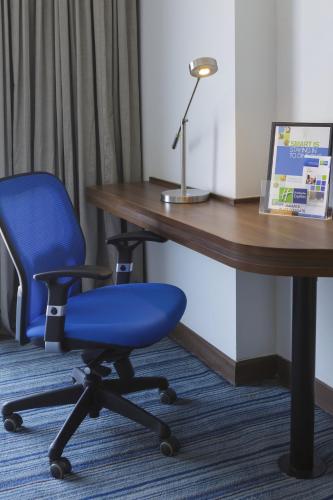 a blue office chair sitting next to a wooden desk at Holiday Inn Express Jakarta Pluit Citygate by IHG in Jakarta