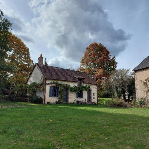 ein kleines weißes Haus mit einem grünen Hof in der Unterkunft Maison Figuier - Cottage anglais in Argent-sur-Sauldre