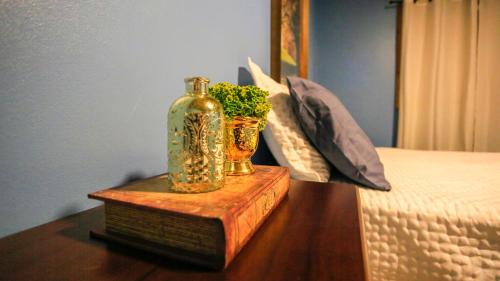 a bottle and a vase on a table next to a bed at Chalé Casa de Pedra, Vivenda Serra Velha, Chalés de Montanha in Timbe do Sul