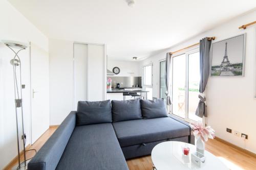 un salon avec un canapé bleu et une table dans l'établissement Le Marnois-Gare, à Noisy-le-Grand