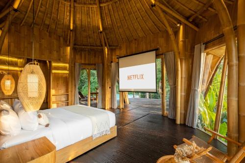 Jungleight Bali في تيغالالانغْ: غرفة نوم بسرير في غرفة بشاشة
