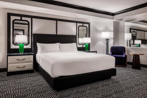 a bedroom with a large bed and a blue chair at Caesars Palace Hotel & Casino in Las Vegas