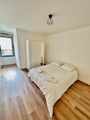 une chambre avec un grand lit blanc et du parquet dans l'établissement Magnifique appartement à Bagnolet-Paris 102, à Bagnolet