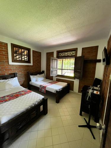 a hotel room with two beds and a window at Finca Hotel Casa Nostra, Villa Manuela in Quimbaya