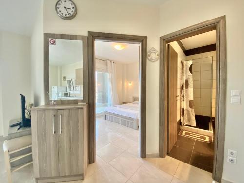 a bathroom with a mirror and a clock on the wall at EllinFos ApartHotel in Hanioti