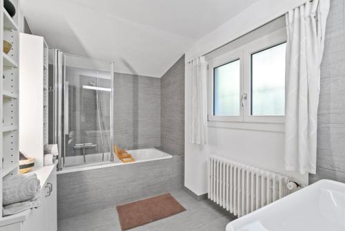 baño blanco con bañera y ventana en A&Y Chalet zum goldenen Hirsch en Davos