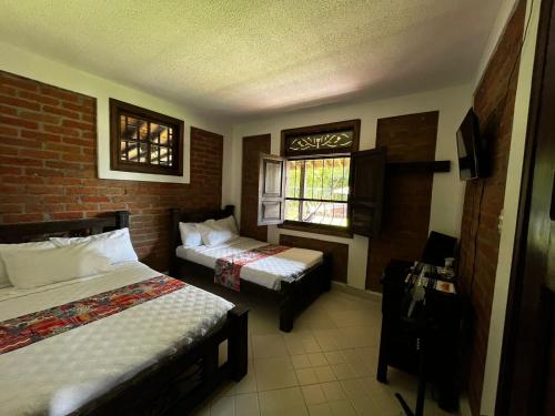 a hotel room with two beds and a window at Finca Hotel Casa Nostra, Villa Manuela in Quimbaya