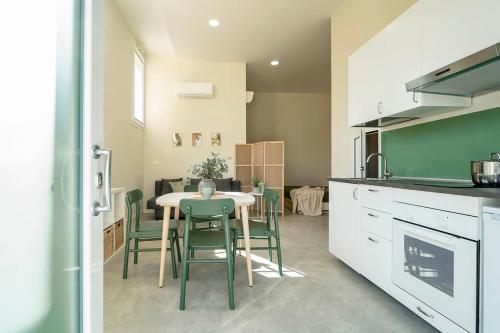 a kitchen with a table and some green chairs at casadelfalegname ABETE in San Giovanni in Bosco