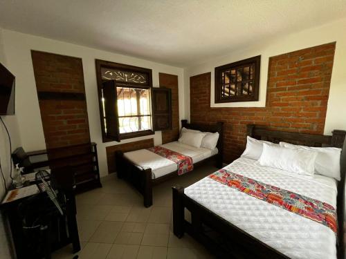 a bedroom with two beds and a brick wall at Finca Hotel Casa Nostra, Villa Manuela in Quimbaya