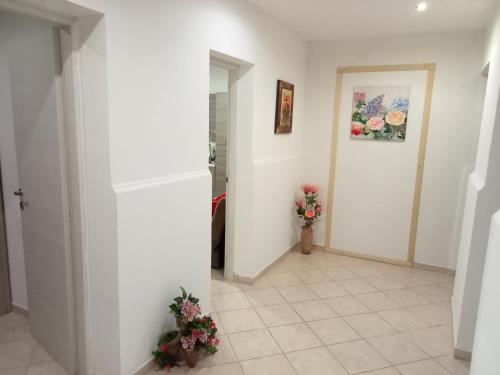 a hallway with white walls and flowers on the floor at Appartamento Giglio in Trapani