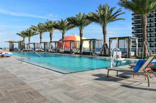 a pool on the roof of a building with palm trees at Zen 2-Bedroom Ocean View at Lyfe Resort in Hollywood