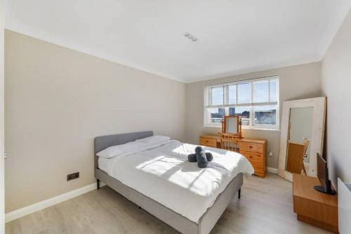 ein Schlafzimmer mit einem Bett, einer Kommode und einem TV in der Unterkunft Luxury Apartment in Kingston in Kingston upon Thames
