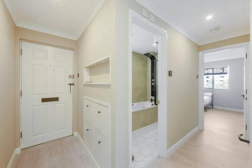 La salle de bains est pourvue d'une douche et d'une porte blanche. dans l'établissement Luxury Apartment in Kingston, à Kingston upon Thames