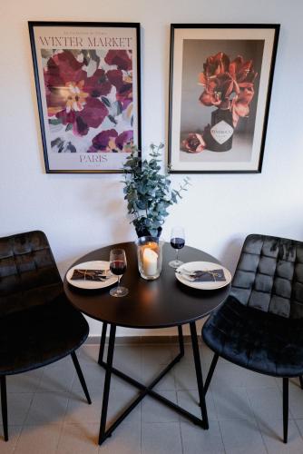 a table with wine glasses and a vase with flowers on it at Balkontraum für 4 am Sieben-Seen-Center in Schwerin