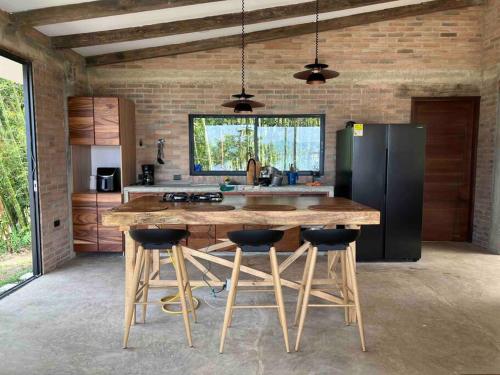 uma cozinha com uma grande mesa de madeira com bancos de bar em Casa campestre Lago Calima em Calima