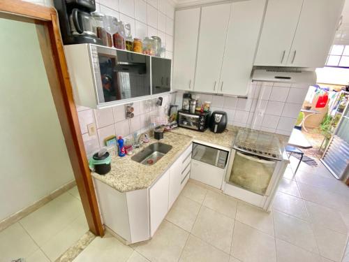 a small kitchen with white cabinets and a sink at Portal do Jaragua in Belo Horizonte