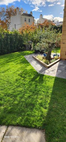 a yard with green grass and a building at La Casa Rosa Cheltenham - free parking close to racecourse in Cheltenham
