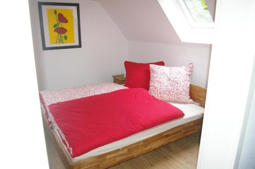 Schlafzimmer mit einem Bett mit roter Bettwäsche und Kissen in der Unterkunft Ferienwohnung Knusperhaus in Xanten