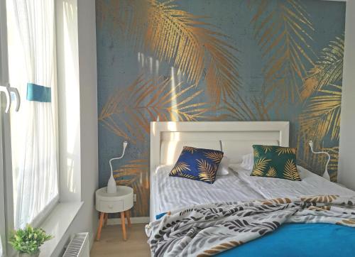 1 dormitorio con 1 cama con papel pintado tropical en Apartamenty Wybrzeże Laguna en Ustronie Morskie