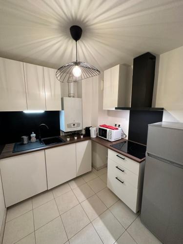 a kitchen with white cabinets and a light hanging from the ceiling at Magnifique appartement à Bagnolet-Paris 102 in Bagnolet