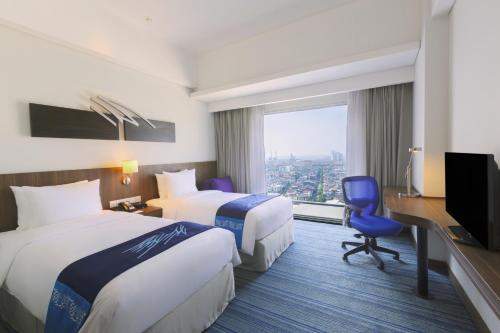a hotel room with two beds and a desk and a tv at Holiday Inn Express Jakarta Pluit Citygate by IHG in Jakarta