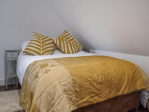 a bed with a yellow blanket and pillows on it at The Loft At Tall Trees in Welton