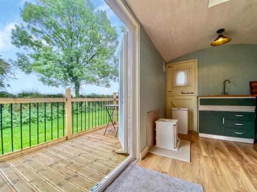 a kitchen with a balcony with a large window at Ivy Shepherds Hut - Uk45590 in Seend