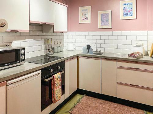 a kitchen with white appliances and pink walls at The Grooms Cottage-uk45659 in Bishops Castle