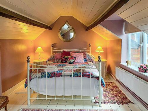 1 dormitorio con cama con espejo y ventana en The Grooms Cottage-uk45659 en Bishops Castle