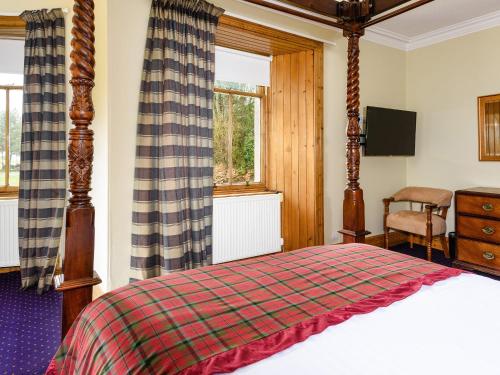 a bedroom with a bed and a tv and a window at Gatehouse Lodge in Moulin