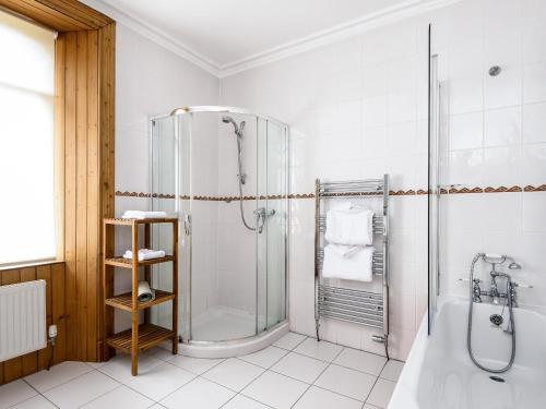 een witte badkamer met een douche en een bad bij Gatehouse Lodge in Moulin