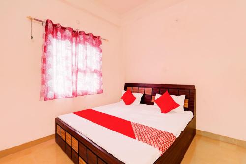 a bedroom with a bed with red pillows and a window at OYO Flagship Shine Hotel in Chinhat