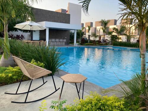 a swimming pool with two chairs and an umbrella at Casa vacacional familiar in Naranjo