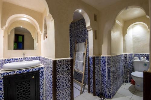 Łazienka wyłożona jest niebieskimi i białymi kafelkami oraz umywalką. w obiekcie Riad Arabesque w Marakeszu