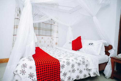 ein rotes und weißes Bett in einem Zimmer in der Unterkunft Arusha Giraffe Lodge in Arusha
