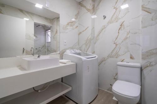 ein weißes Bad mit einem Waschbecken und einem WC in der Unterkunft Apto com churrasqueira privativa Itapema-SC CPE203 in Itapema
