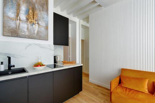 une cuisine avec une chaise orange à côté d'un évier dans l'établissement Appartement Design île St Louis - Welkeys, à Paris