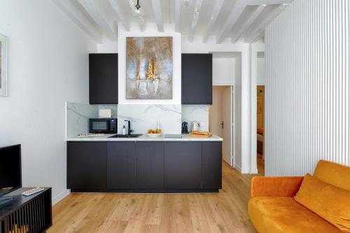 a kitchen and living room with an orange couch at Designer apartment on St Louis Island in Paris - Welkeys in Paris