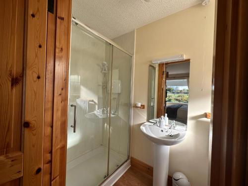 a bathroom with a glass shower and a sink at House in Glenties in Glenties