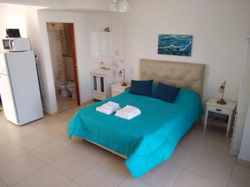 a bedroom with a bed with blue sheets and a refrigerator at Juana I in Villa Elisa