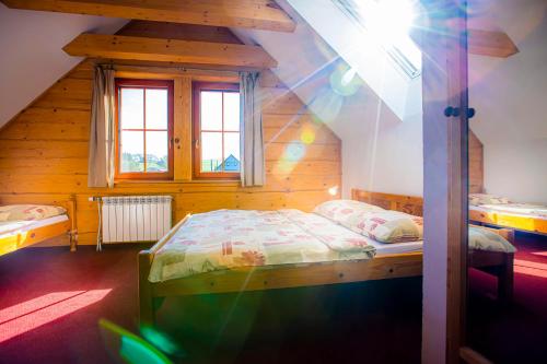 a bedroom with two beds in a wooden cabin at Holiday Raj in Bešeňová