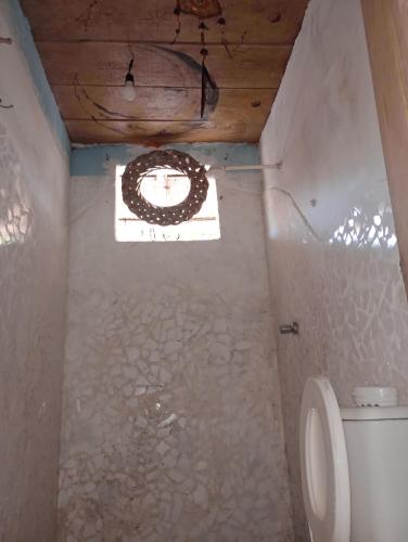 a bathroom with a toilet and a window at Suíte Beija-flor in Camaçari