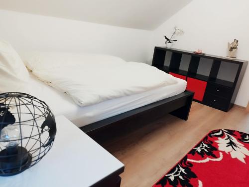 a bedroom with a white bed and a red rug at Ferienwohnung Fabian in Stainach