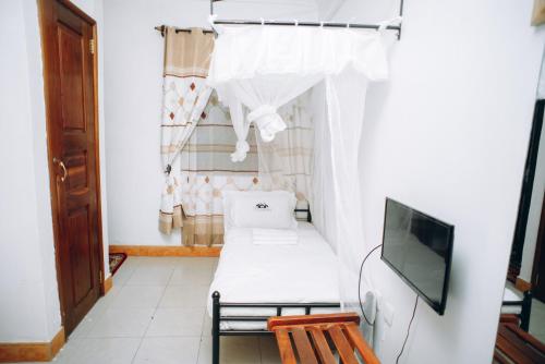 a small room with a bed and a tv at Arusha Giraffe Lodge in Arusha