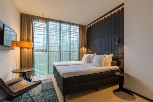 une chambre d'hôtel avec un lit et une chaise dans l'établissement Leonardo Hotel Groningen, à Groningue
