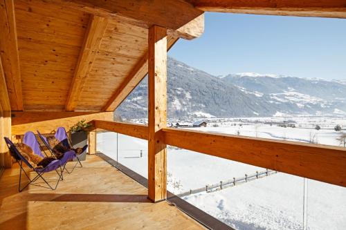 a view from the balcony of a wooden house with chairs at SportLodge GOLF SUITE - Cozy Apartment with Shared Pool, Whirlpool & Sauna, presented by AlpenLuxus in Kleinboden