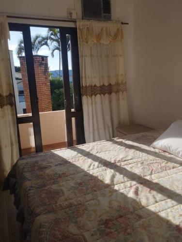 um quarto com uma cama e uma grande janela em Casa Praia Brava Florianópolis. em Florianópolis