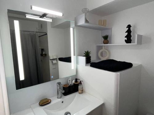 une salle de bain blanche avec un lavabo et un miroir dans l'établissement Votre Pied-à-Terre en Bord de Mer, à Sète