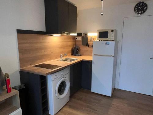 Il comprend une cuisine équipée d'un lave-linge et d'un réfrigérateur blanc. dans l'établissement Votre Pied-à-Terre en Bord de Mer, à Sète